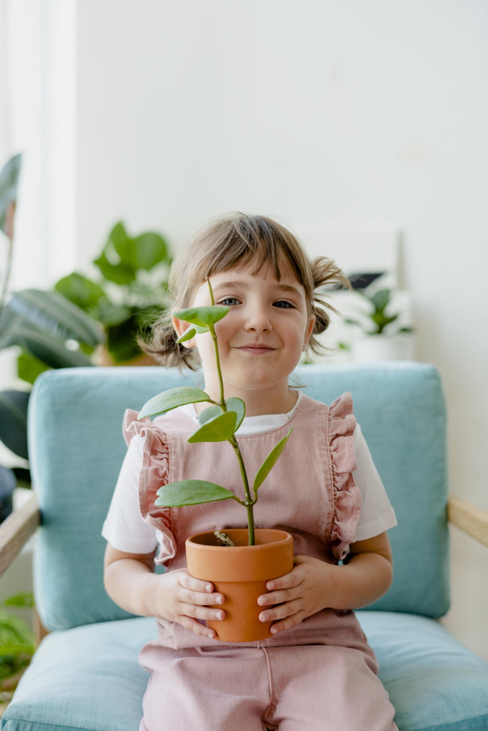Cute girl kid holding potted plants at home