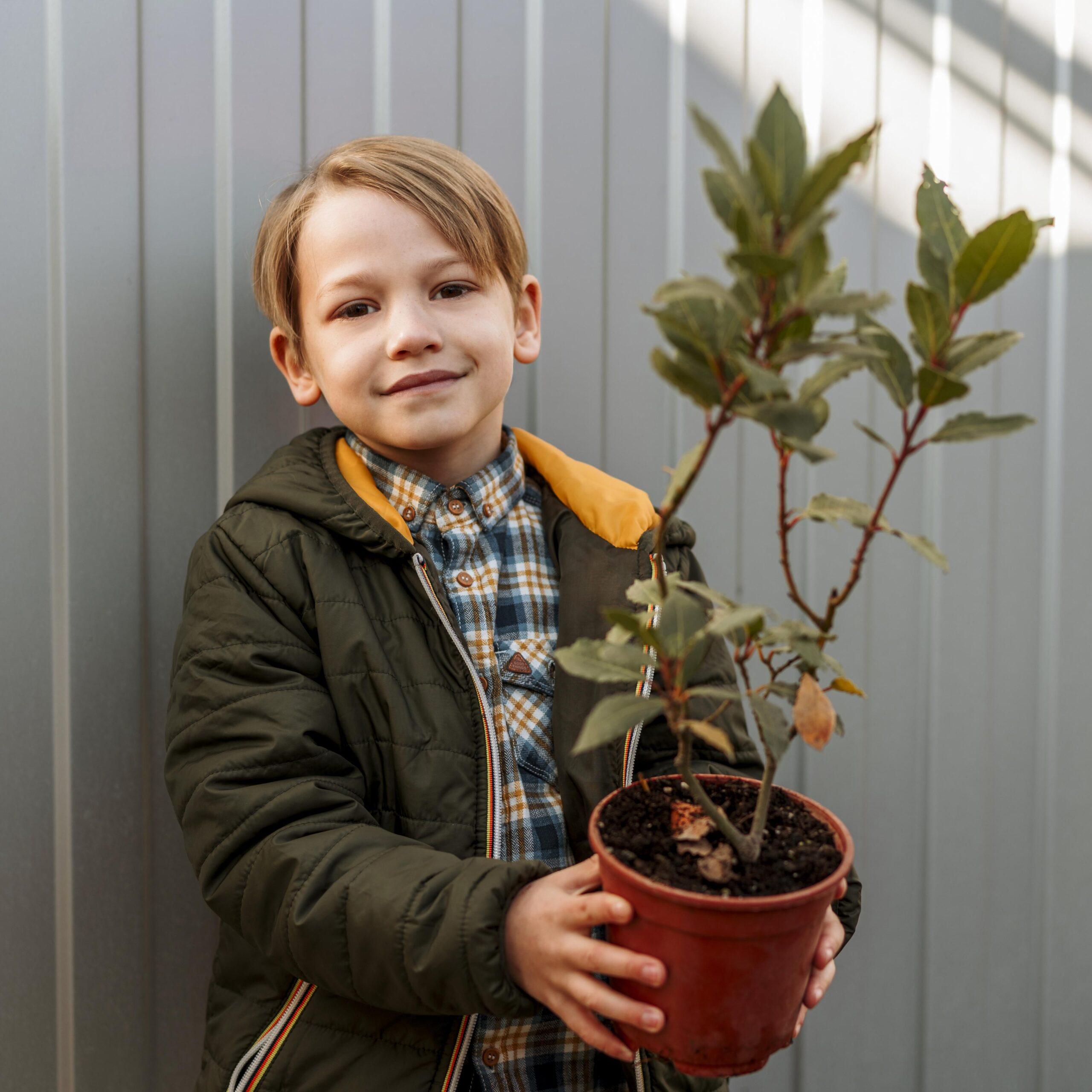ragazzo-di-smiley-che-tiene-pentola-con-piccolo-albero